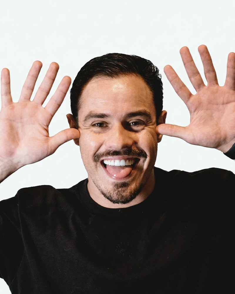 Juan AUEI rindo com as mãos ao lado do rosto